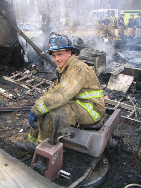 Robert sits on a burned up lawnmower while taking a breather at trailer fire