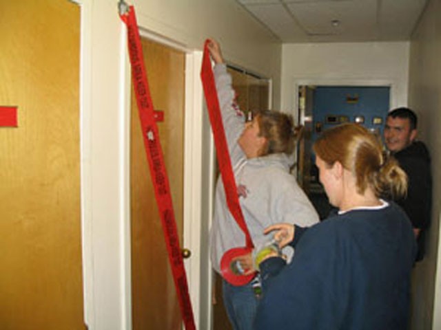 Katie, Megan and Jeff tape off the hot zone, which happens to be the women's bathroom.