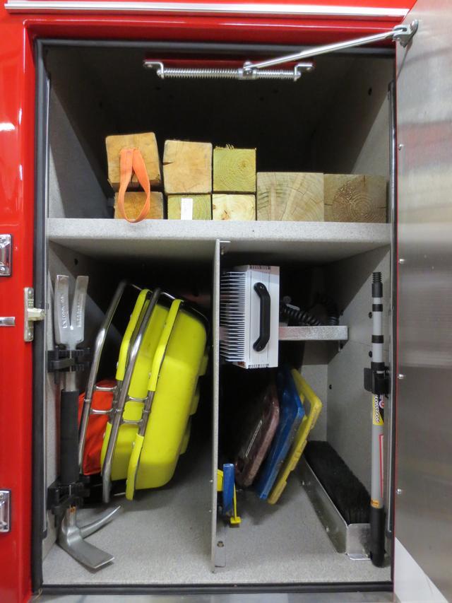 Transverse cab compartment houses both stokes baskets, tripod lights, back boards, brooms, officers halligan bar, long timbers, long roof hooks and the Little Giant Ladder platform