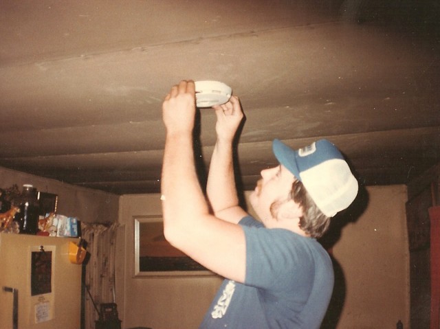 Dan Emmart checking a smoke smoke detector